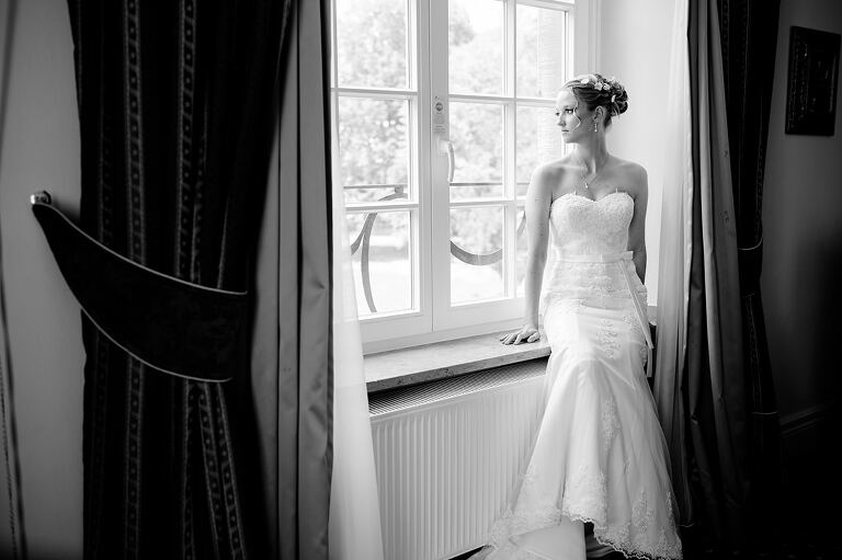 Braut sitzt auf dem Fensterbrett und schaut aus dem Fenster - Sportschloss Velen