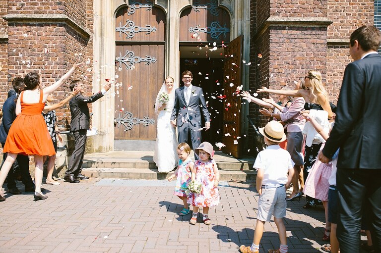 Braut und Bräutigam kommen aus der Kirche und werden mit Blumen beworfen - Sportschloss Velen