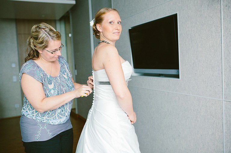 Schwester der Braut hilft der Braut in das Kleid