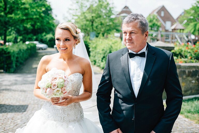 Braut mit ihrem Vater vor der Kirche