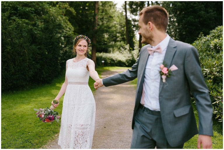 Braut und Bräutigam gehen Hand in Hand durch den Park ©Hochzeitsfotograf Burg Hülshoff