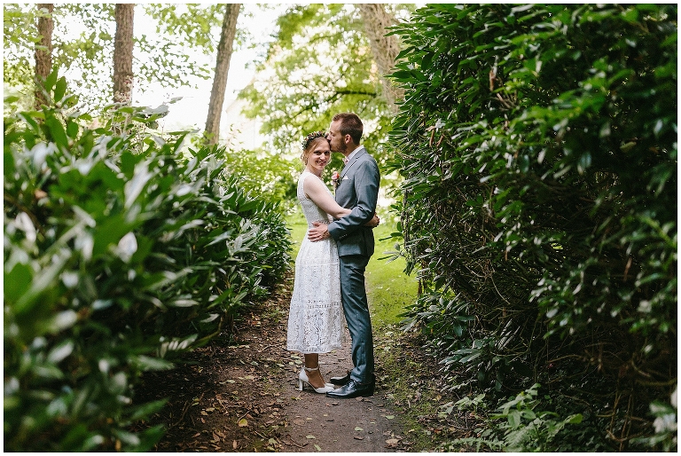 Brautpaar steht zwischen zwei grünen Büschen ©Hochzeitsfotograf Burg Hülshoff