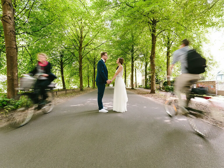 Brautpaar auf der Promenade mit dem Hochzeitsfotograf Münster und 2 Fahrradfahrern